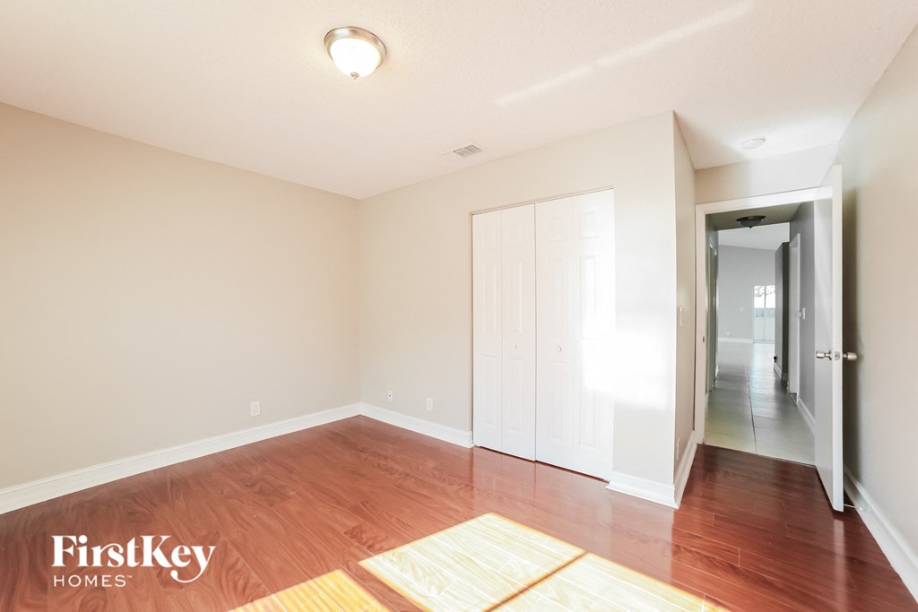 a living room with a hardwood floor and a door to a hallway