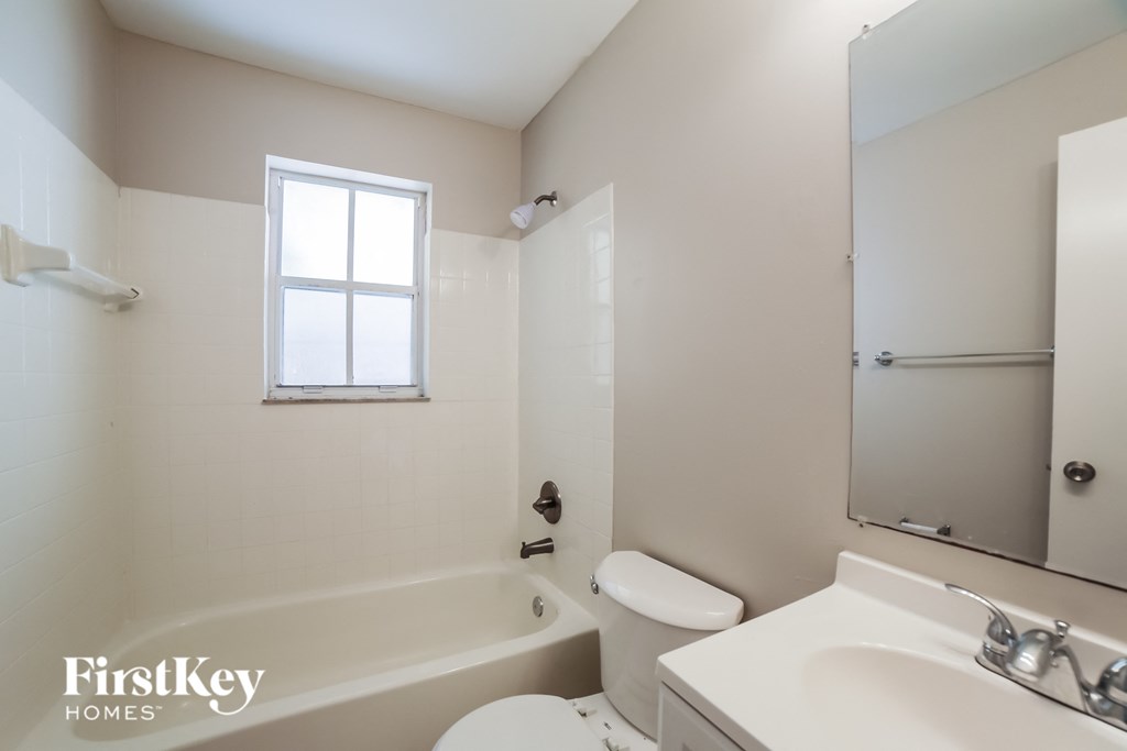 a bathroom with a toilet sink and tub and a mirror