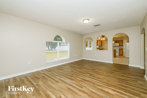 A spacious room with wooden flooring and a large window.