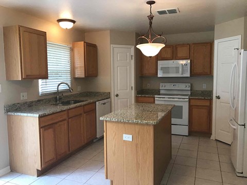 A kitchen with wooden cabinets and a granite countertop.