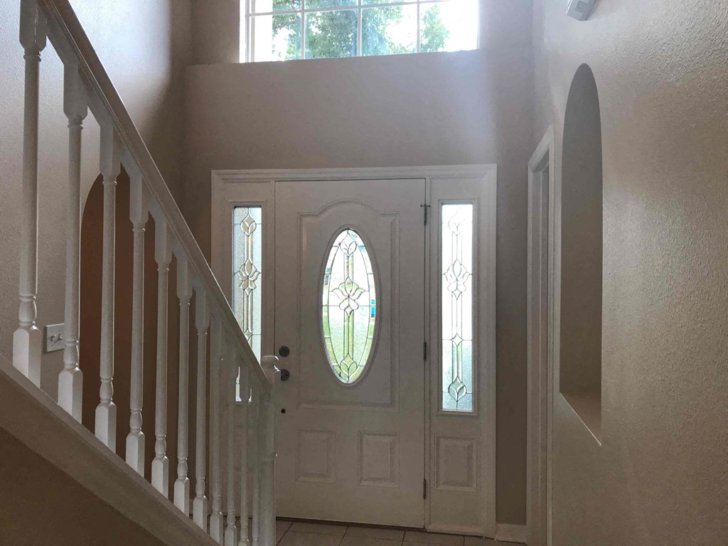 A white door with a stained glass window is at the end of a staircase.