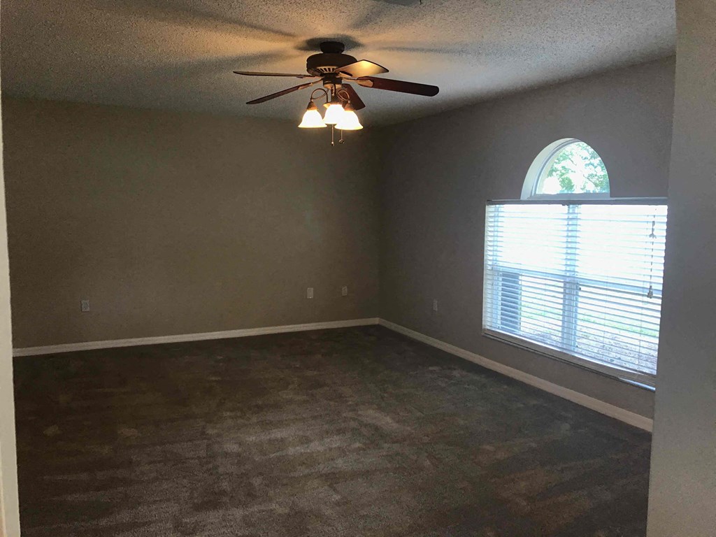 A room with a ceiling fan and a window with blinds.