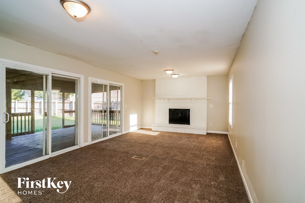 an empty living room with a fireplace and glass sliding doors