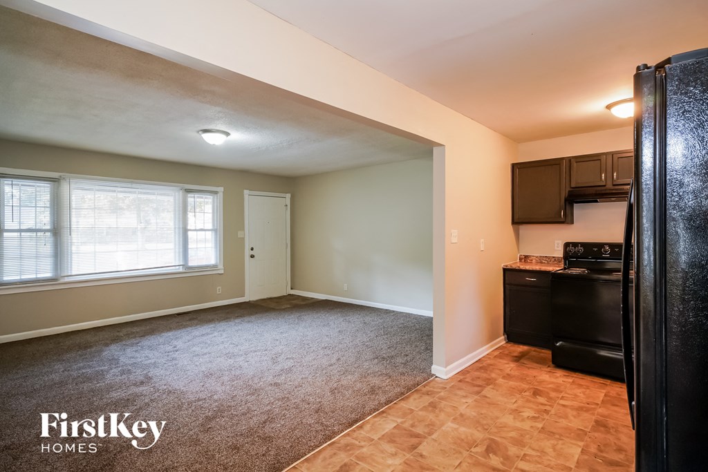 an empty kitchen with a large window and a black refrigerator