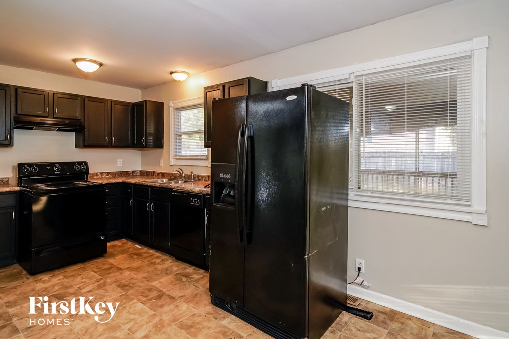 a kitchen with black appliances and a large window