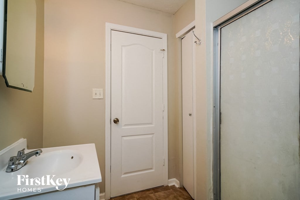 a bathroom with a sink and a shower and a white door