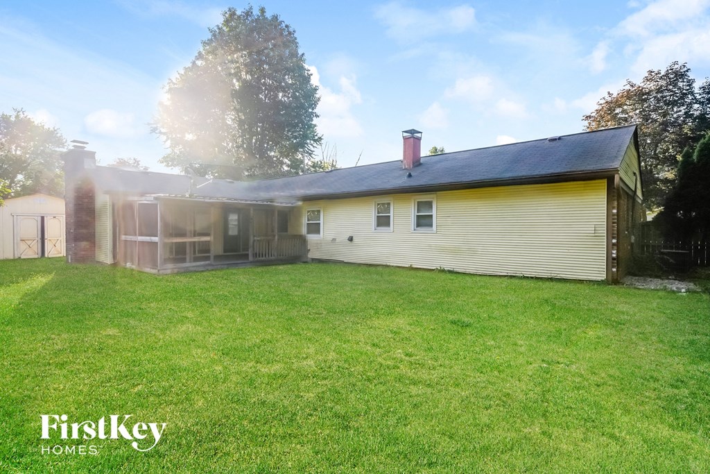a backyard with a yellow house and a green lawn