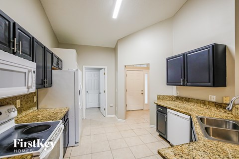 A kitchen with granite countertops and black cabinets.