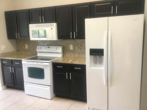 a kitchen with white appliances and black cabinets