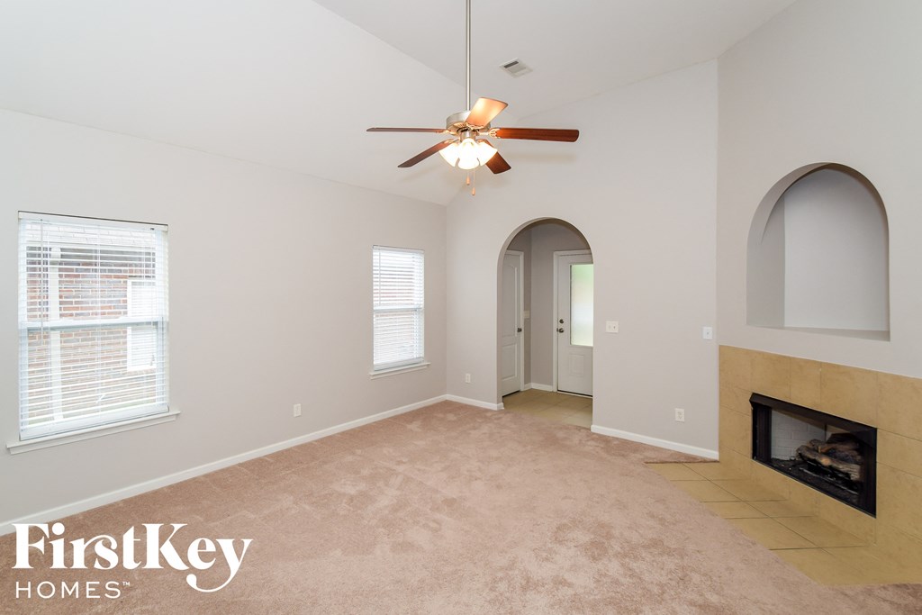 A spacious living room with a fireplace and a ceiling fan.