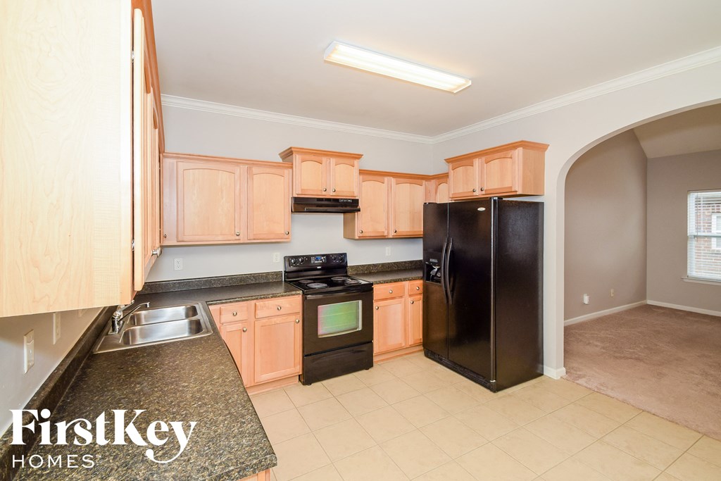 A kitchen with wooden cabinets and a black refrigerator.