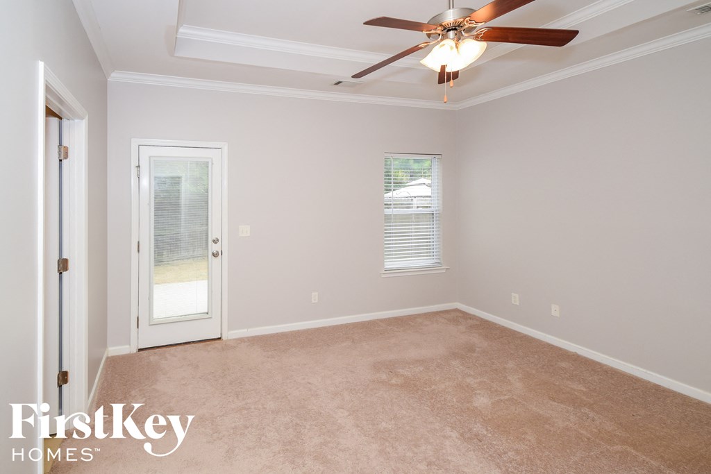 A room with a ceiling fan and a door leading outside.