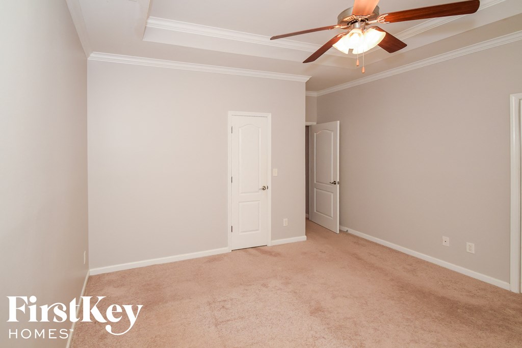 A room with a ceiling fan and two doors.