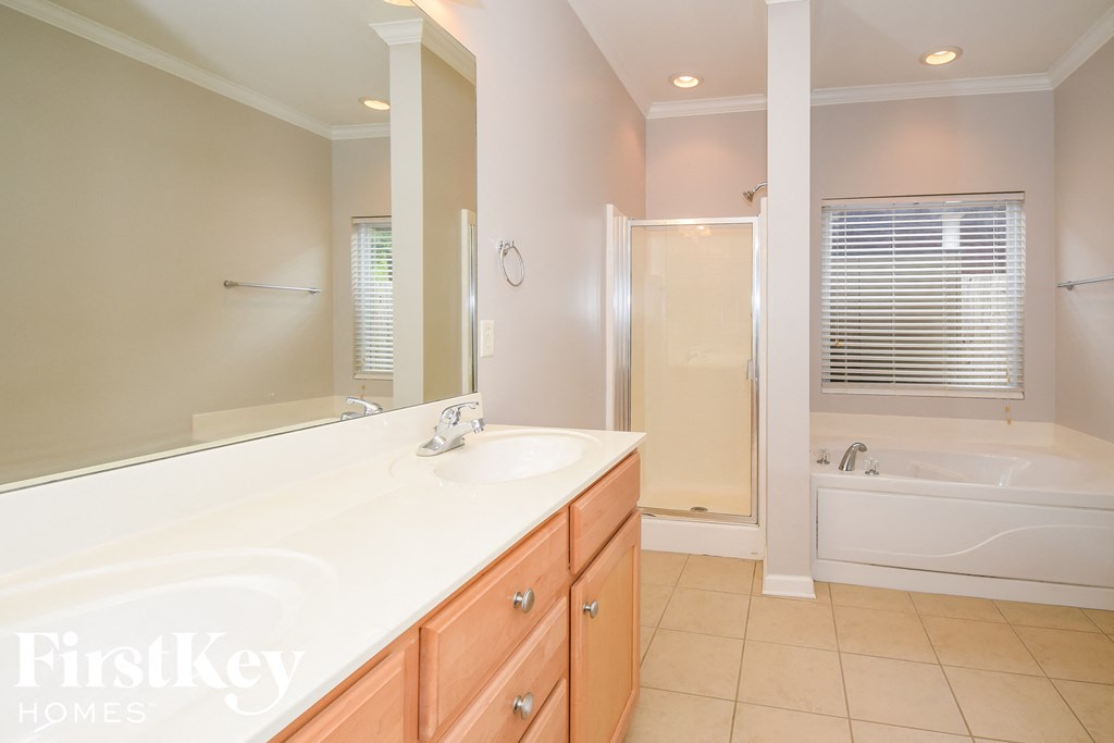 A bathroom with a large mirror, a sink, and a bathtub.