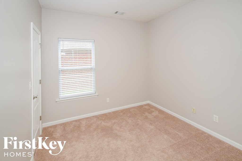 A room with a carpeted floor and a window with blinds.