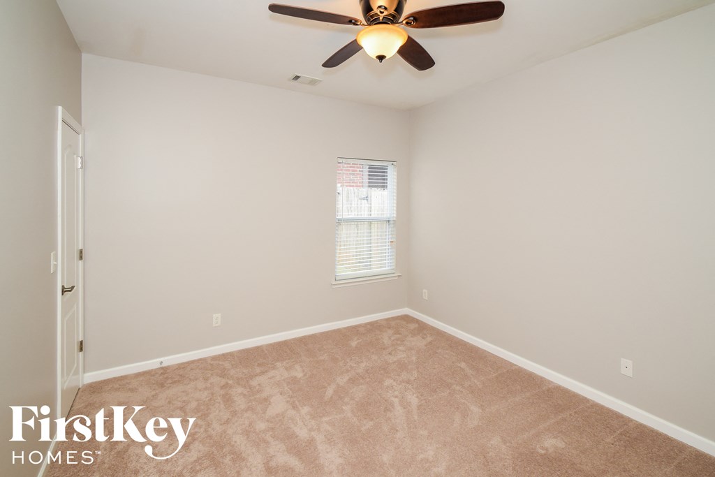 A room with a ceiling fan and a window with blinds.
