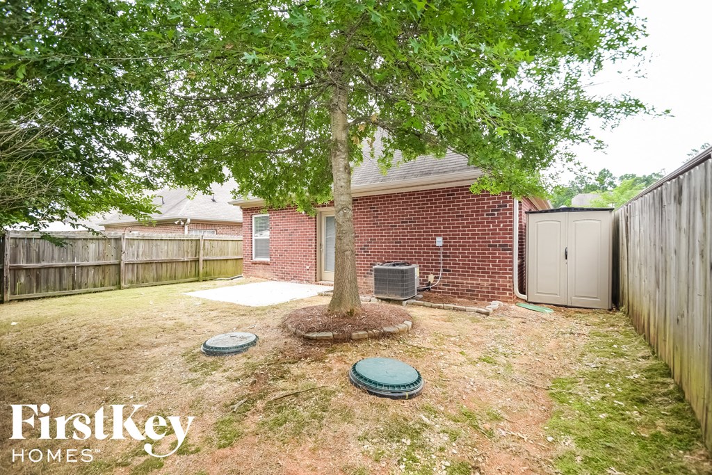 A tree in a yard with a brick house in the background.