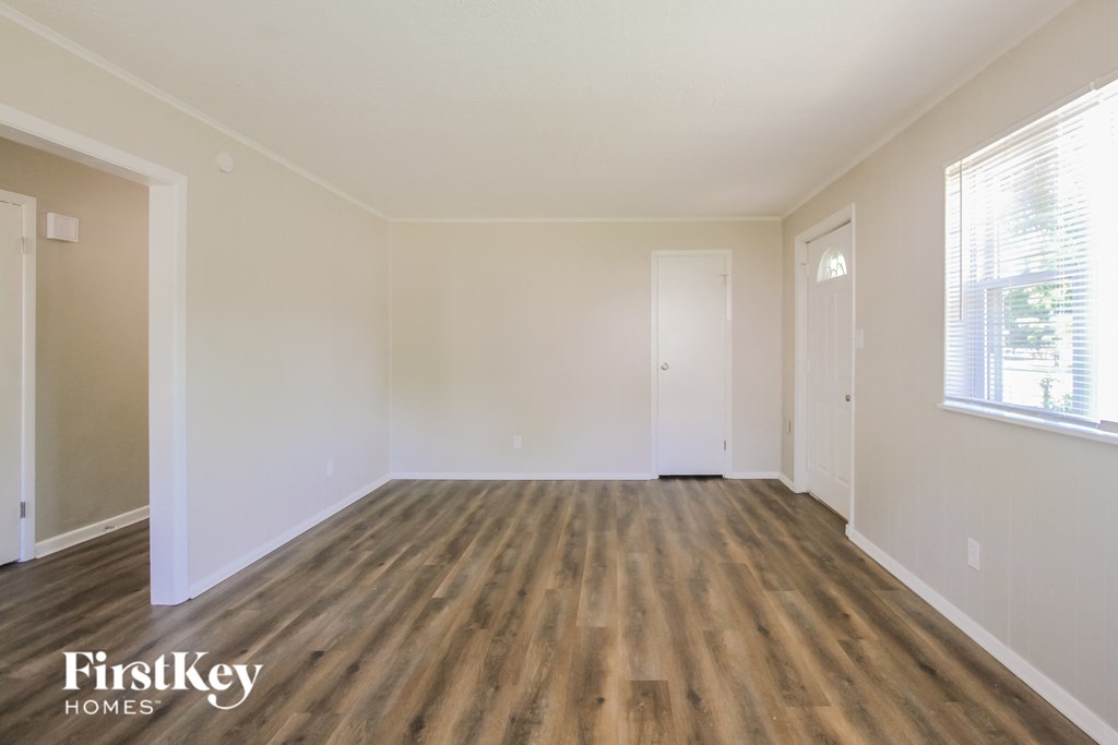 an empty living room with wood floors and white walls