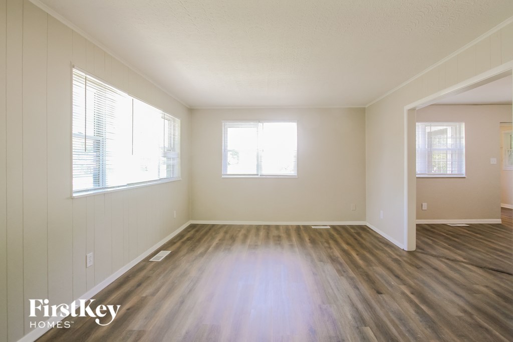 an empty living room with wood floors and a window