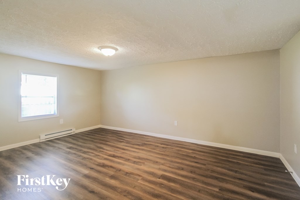 a living room with wood floors and white walls and a window