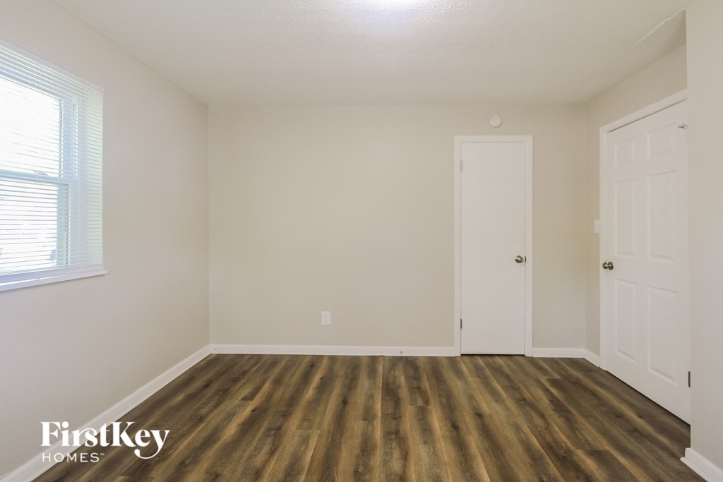 a bedroom with white walls and wood flooring and a door