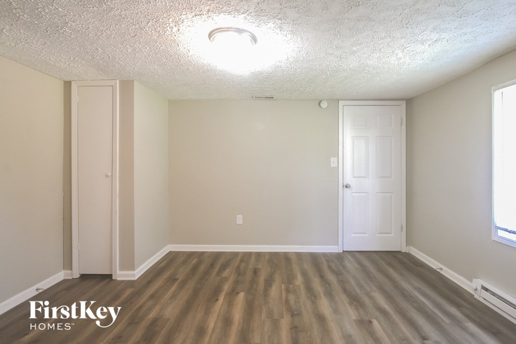 the living room of an apartment with wood flooring and a white door