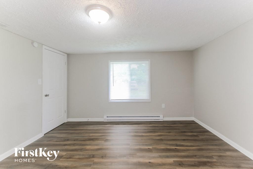 the living room of an empty house with wooden floors and a window