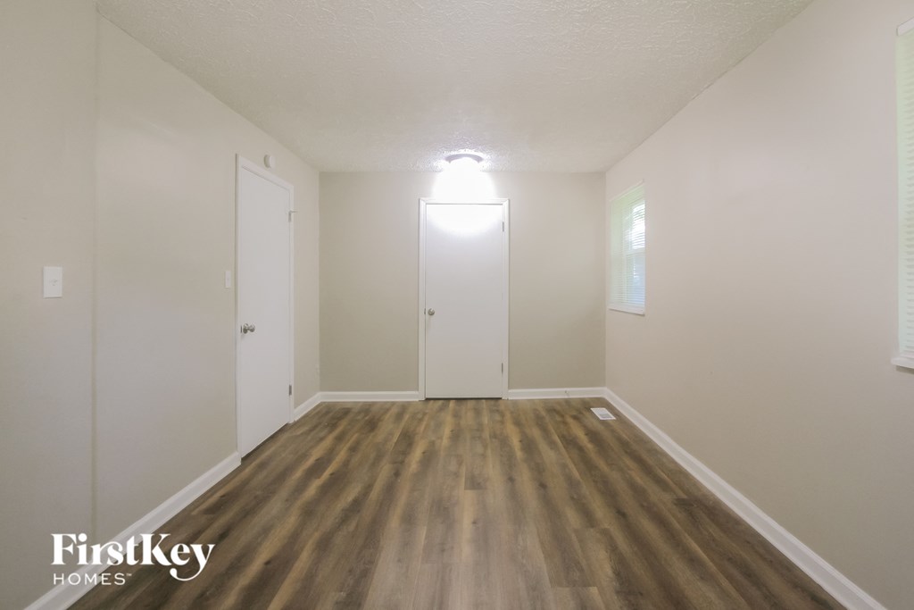 an empty living room with wood flooring and white walls