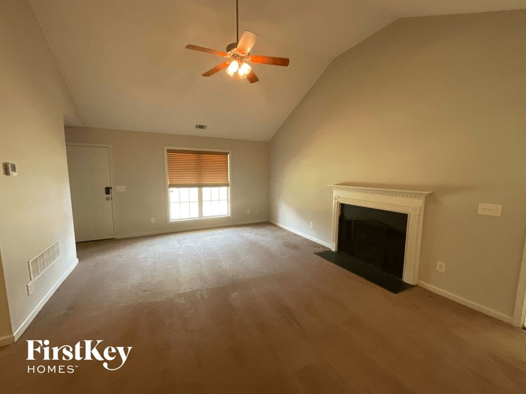 A living room with a fireplace and a ceiling fan.
