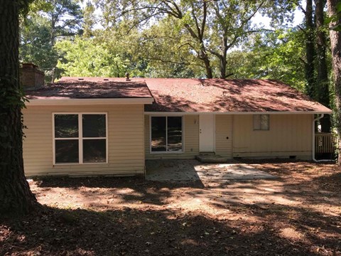 the front of the house with the driveway and trees