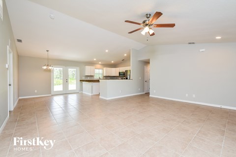 A spacious living room with a ceiling fan and lighting fixtures.