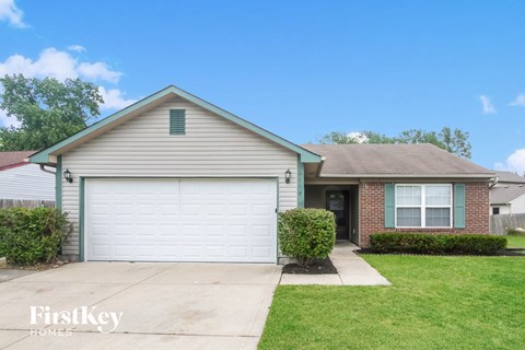 a white house with a white garage door in front of a green lawn