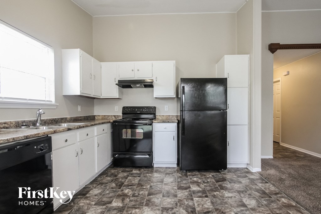 a kitchen with white cabinets and a black refrigerator and stove