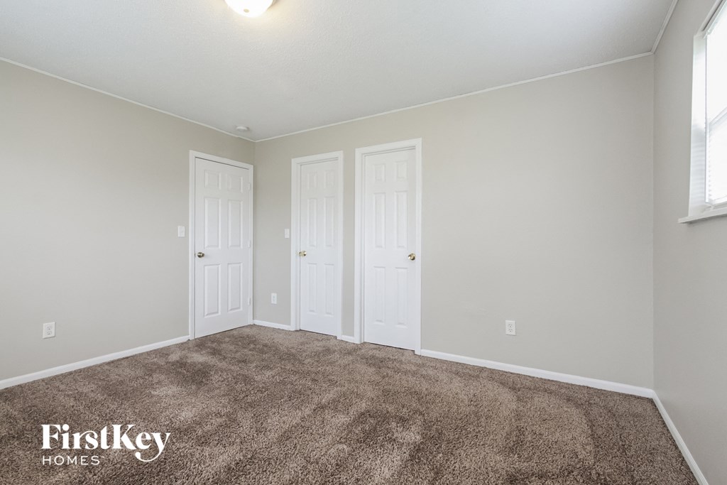a bedroom with two doors and a carpeted floor