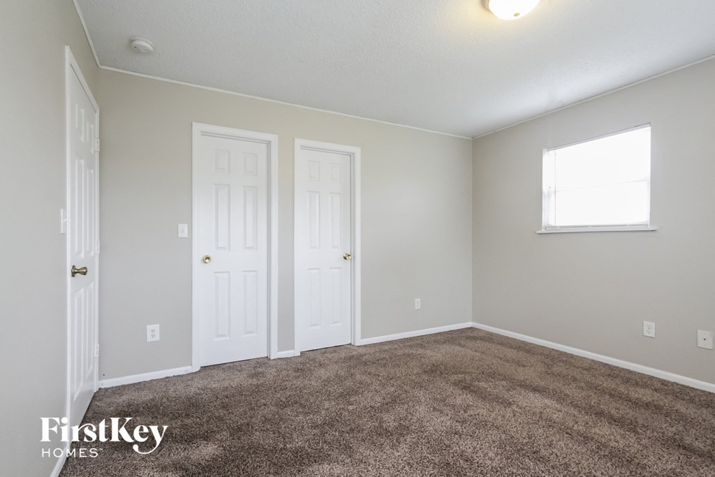a carpeted living room with two doors and a window