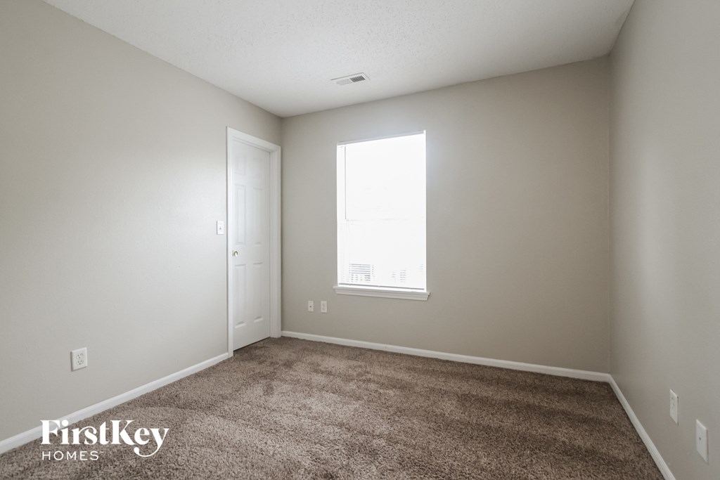 a bedroom with a carpeted floor and a window