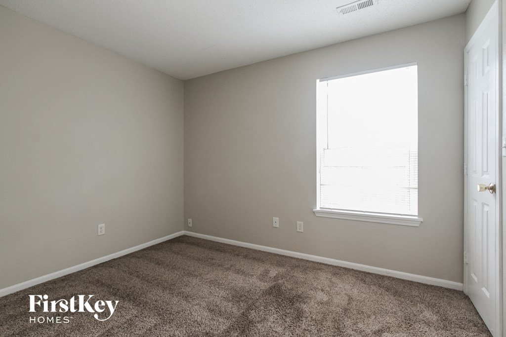 a carpeted room with a window and a door