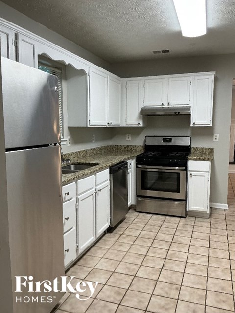 A kitchen with white cabinets and a stainless steel refrigerator.