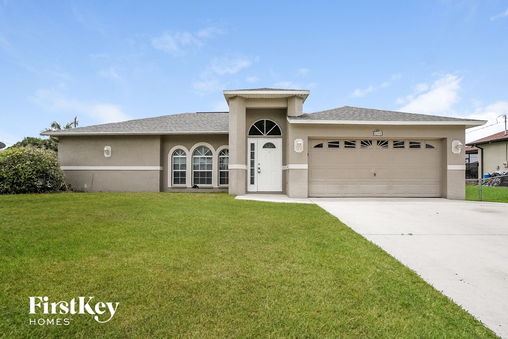 a beige house with a garage and a lawn