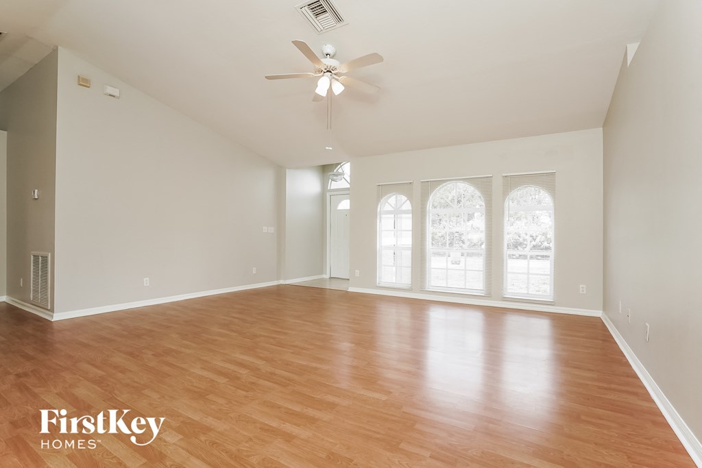 an empty living room with wood floors and a ceiling fan