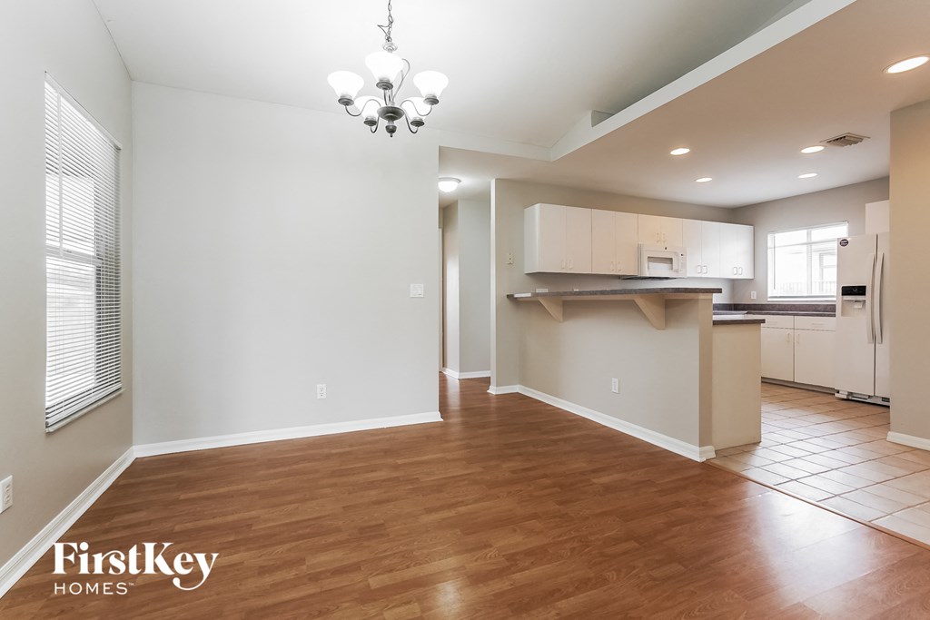 a kitchen and living room with a wood floor and white cabinets