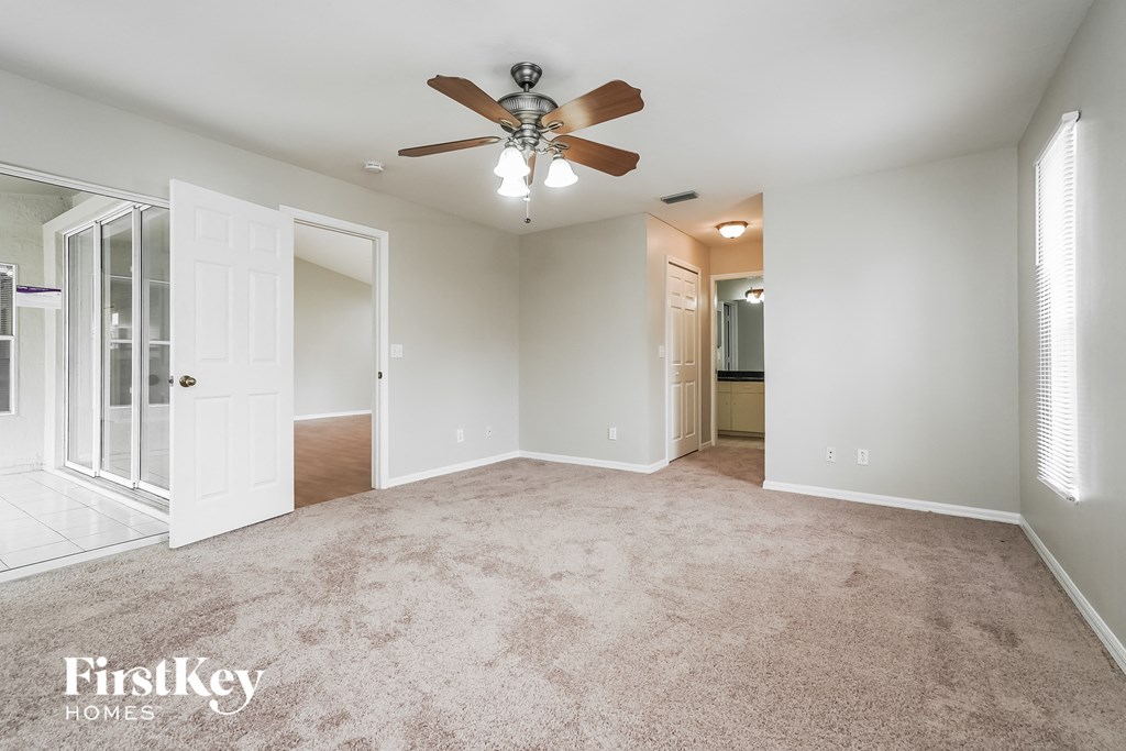 an empty living room with a ceiling fan and a closet