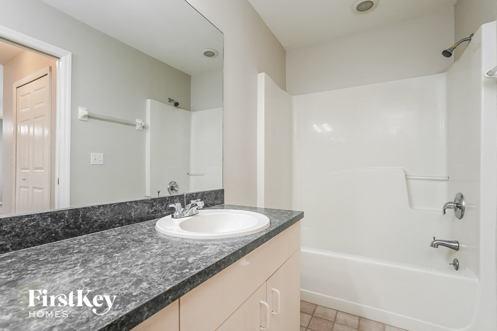 a bathroom with a sink and a shower and a mirror