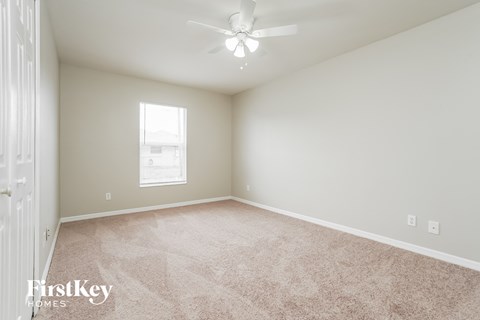 a spacious living room with carpet and a ceiling fan