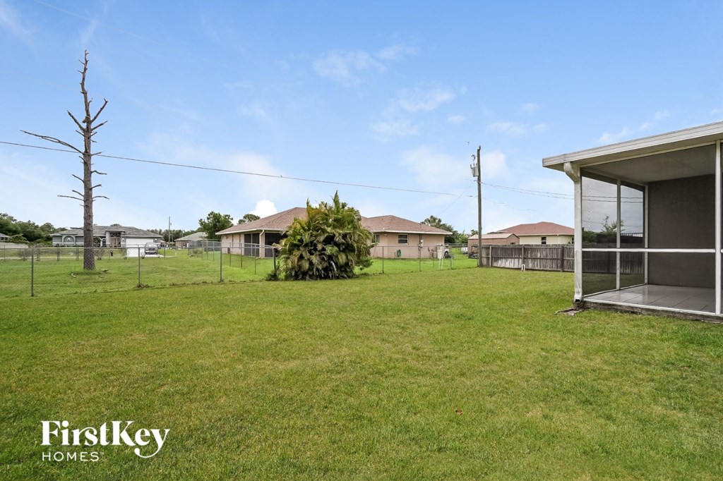 a yard with a fence and houses in the background