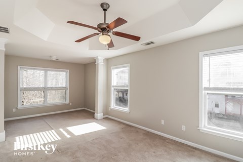 a living room with a ceiling fan and two windows