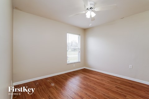 the spacious living room with hardwood floors and a ceiling fan
