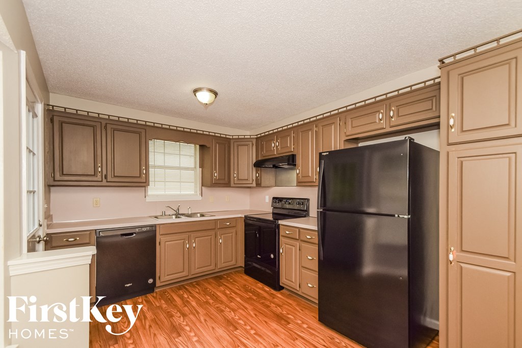 a kitchen with brown cabinets and a black refrigerator