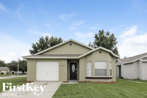 A small house with a garage door and a window is for sale.