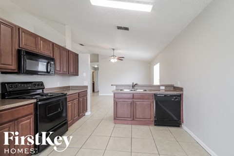 A kitchen with brown cabinets and black appliances.
